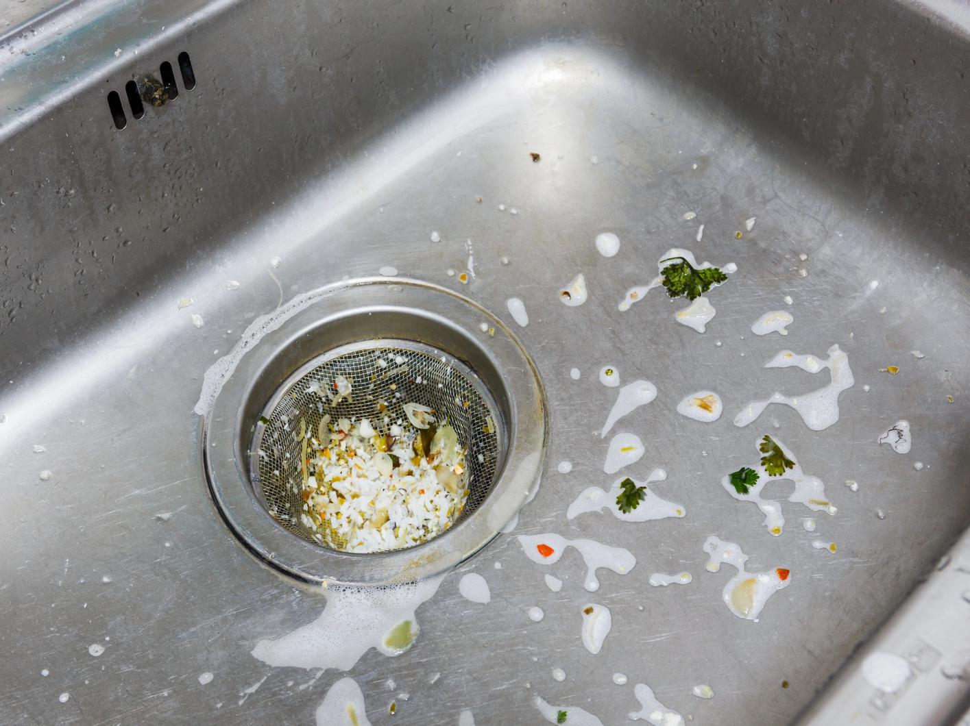 Kitchen sink strainer catching food debris, a maintenance tip for Regina drains.